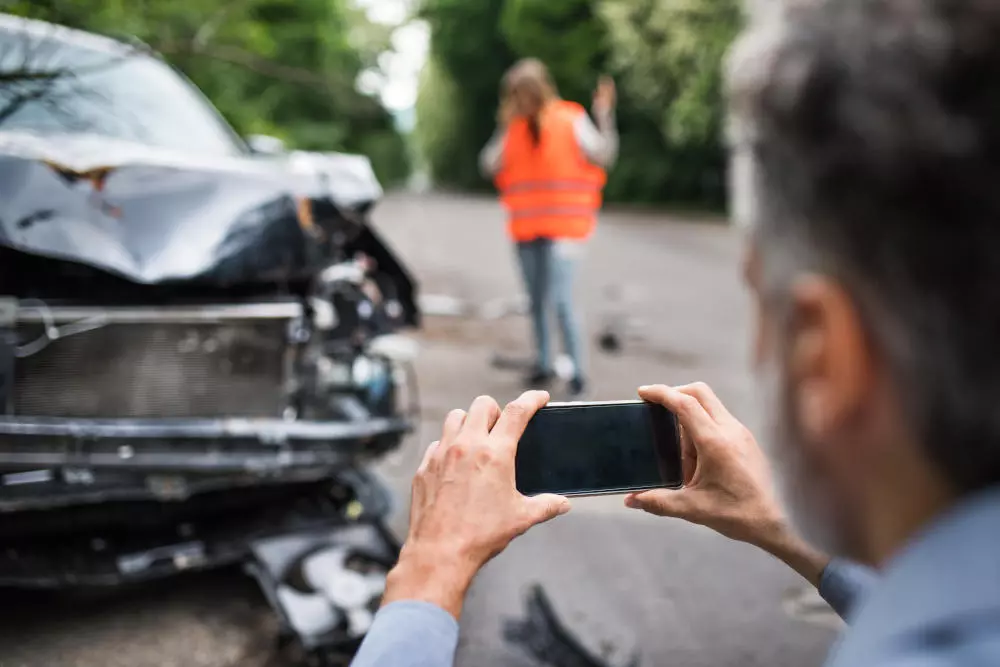 A crash investigator takes pictures of a car accident. Traffic accident investigation is crucial to settling insurance claims.